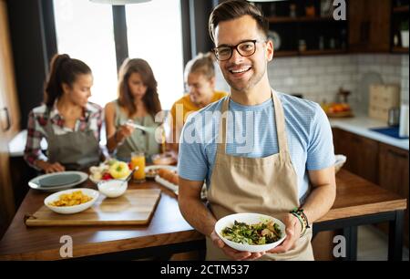 Group of happy friends having fun in kitchen, cooking food together Stock Photo