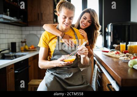 Beautiful young couple having fun in the kitchen while cooking. Stock Photo