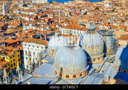 Top aerial view of Venice city old historical centre with domes of Basilica di San Marco or Cathedral of Saint Mark Roman Catholic church and red tiled roofs buildings, Veneto Region, Northern Italy
