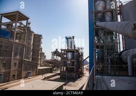 Mynaral/Kazakhstan - April 23 2012: Modern Jambyl Cement plant. Factory buildings and silos on blue sky in back light. Stock Photo