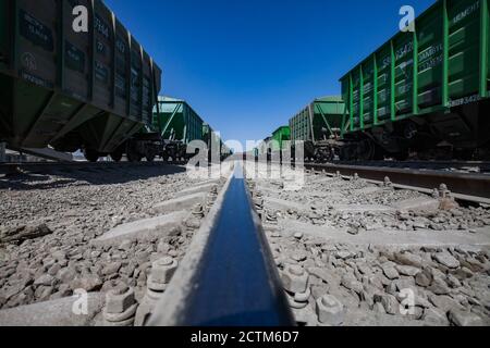 Mynaral/Kazakhstan - April 23 2012:  Jambyl Cement plant. Cargo railway terminal. Close-up of rail. No one. Train cars in desert and dust. On deep blu Stock Photo