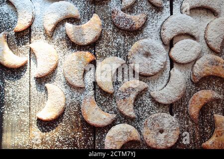 Shortbread New Year's, Christmas cookies in the shape of the moon. A child sprinkles cookies with powdered sugar. Baby and cookies. Child's hands in Stock Photo