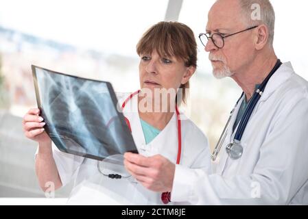 Two doctors examining x-ray report in medical office Stock Photo