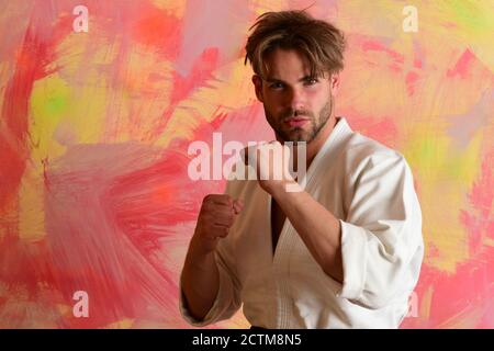 Fighter performing karate stance on colored background. Defence and taekwondo sports concept. Stock Photo