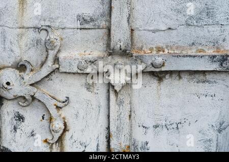 Fragment of ancient peeling and decayed monastery gates with rusty skillfully forged hinges and decorative overlays.  Stock Photo