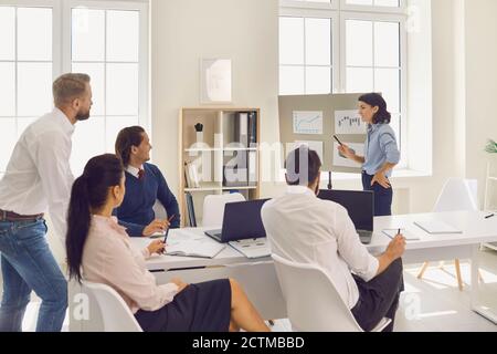 In conference room, young woman head of department speaks at meeting ...