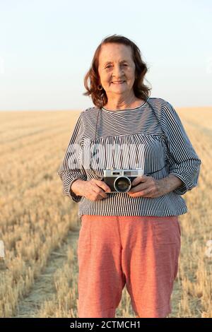 Portrait of an elderly woman with an analog camera in the field. Stock Photo