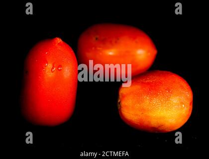 Three ripe red tomatoes isolated on black background Stock Photo