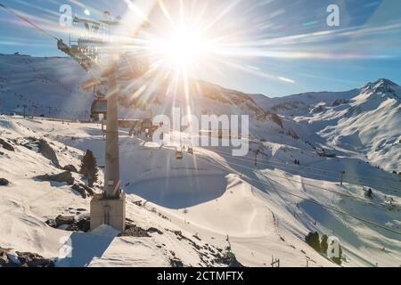 Panoramic view Idalp skiing area with many ski slope, pistes, ski chairlifts gondola against mountain landscape and bright sun lens flare at luxury Stock Photo
