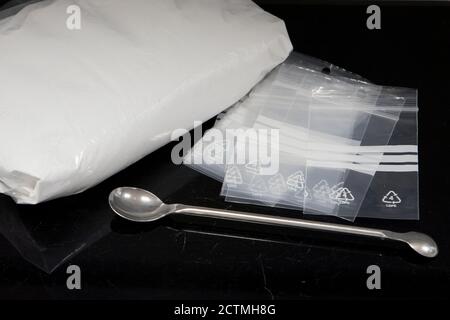 Drug dealing concept with large bag of white powder and several smaller deal bags Stock Photo