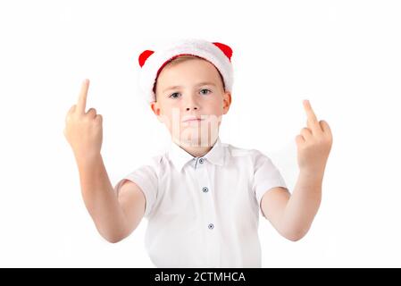 Gesturing boy in santa hat showing middle finger sign, on white studio wall. Stock Photo