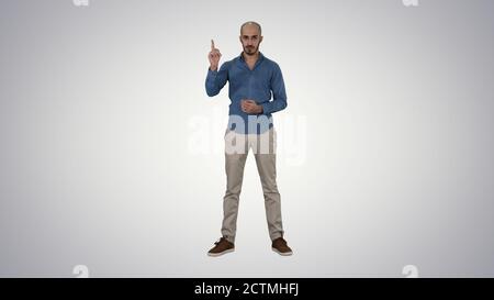 Arabic man in casual making attention gesture finger up on gradi Stock Photo