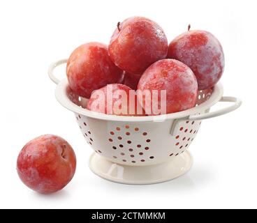 ripe red wet plums in colander isolated on white background Stock Photo