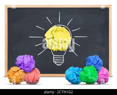 Paper ball forming a lightbulb with other multi-colored paper balls around on a blackboard, black background Stock Photo