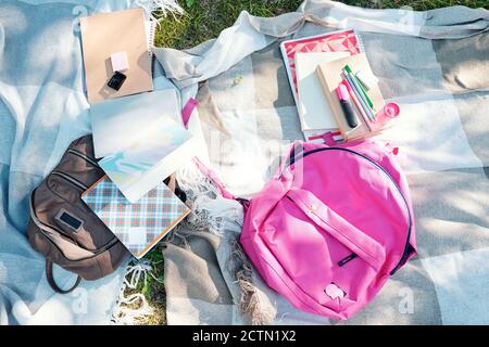 Directly above view of kids stuff such as satchels, workbooks and school supplies on blankets Stock Photo