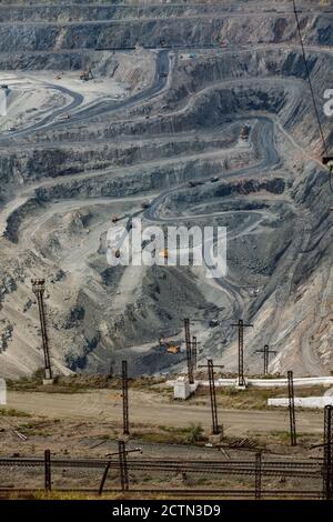 Giant iron ore quarry in Rudny,  Kazakhstan. Open pit mining raw minerals for steel production. Quarry machines, excavators and dump trucks and railro Stock Photo