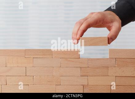 Man placing the last toy block on a wall Stock Photo