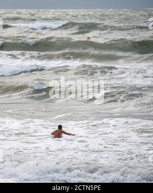 Brighton UK 24th September 2020 - A swimmer braves the sea on a windy day in Brighton with more unsettled weather forecast for Britain over the next few days : Credit Simon Dack / Alamy Live News Stock Photo