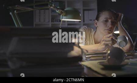 Frustrated woman working in the office at night, she had many cups of coffee and feels exhausted, working overtime concept Stock Photo