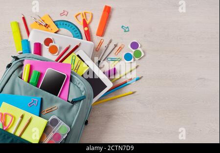 Backpack full with school supplies on a wooden table Stock Photo