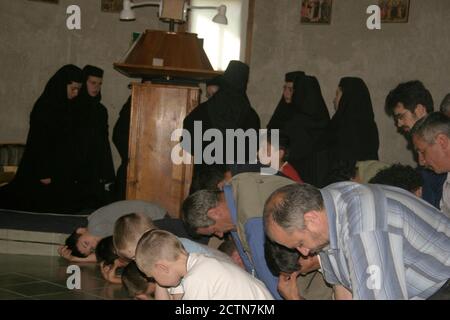 Nuns and believers praying on their knees inside a Christian Orthodox church in Romania Stock Photo