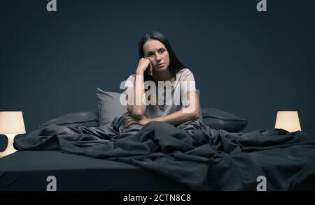 Stressed woman suffering from insomnia, she is sitting in bed and feeling sad Stock Photo