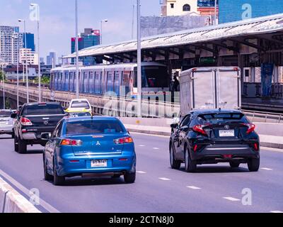 Cars and the BTS Skytrain on Saphan Taksin where it crosses Chao Praya River in Bangkok, Thailand. The name of the skytrain station is also Saphan Tak Stock Photo