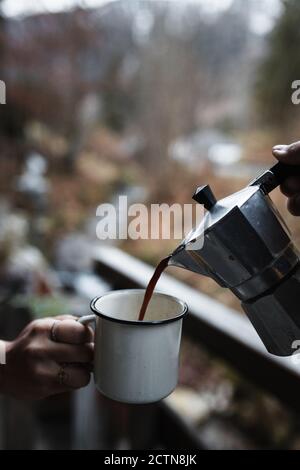 https://l450v.alamy.com/450v/2ctn8jk/crop-anonymous-hiker-pouring-hot-coffee-from-metal-coffeepot-into-enamel-mug-held-by-friend-while-having-break-during-travel-through-autumn-countryside-2ctn8jk.jpg