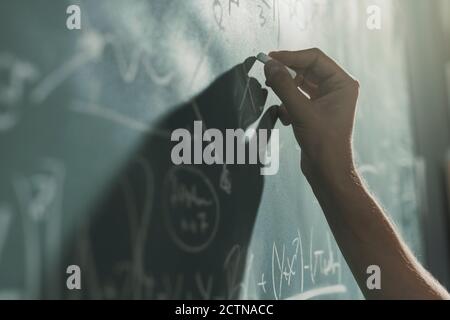 Professor writing mathematical formulas on the chalkboard, hand close up Stock Photo