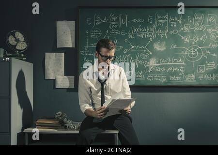 Young researcher studying mathematics in his office, he is checking papers, solving problems and discovering new theories Stock Photo