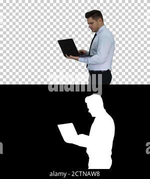 Formal man walking and using laptop, Alpha Channel Stock Photo