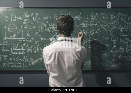 Young mathematician solving problems and writing formulas on the ...