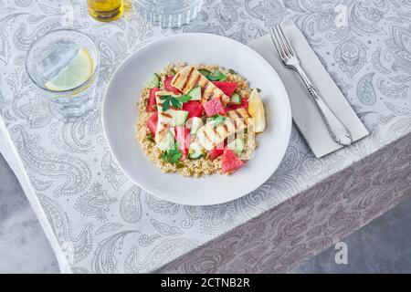 Appetizing Bulgur salad with watermelon and cucumbers in plate served on table for tasty lunch Stock Photo