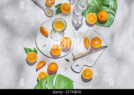 Top view of whole and half of ripe oranges arranged on table with knife and glass with juice Stock Photo