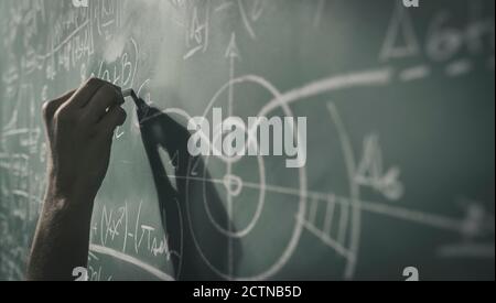Professor writing mathematical formulas on the chalkboard, hand close up Stock Photo