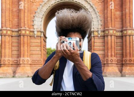 Black man taking a picture while facing the camera with a camera in Arch of Triumph Barcelona Stock Photo