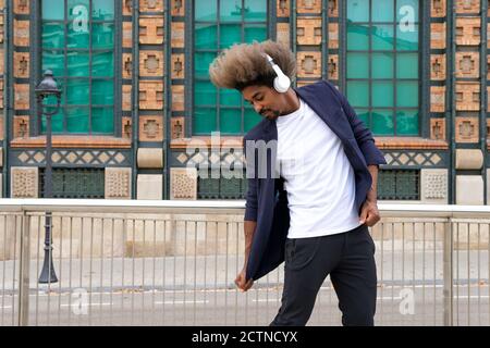 African man dancing while listening to music with a wireless headset in front of a historical building Stock Photo