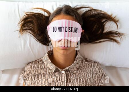 Peaceful female sleeping in eye mask in soft bed in bright modern apartment Stock Photo