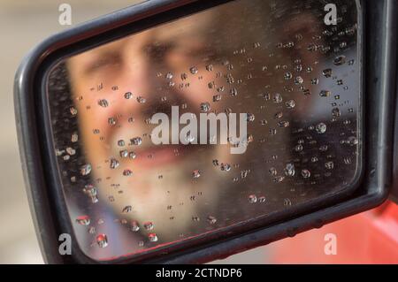 Blurred silhouette of bearded Caucasian senior driver in dirty rearview car mirror Stock Photo