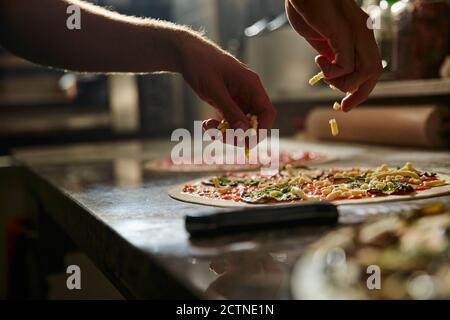 Process of preparation pizza with various vegetables on marble counter with ingredients and utensils in pizzeria kitchen Stock Photo