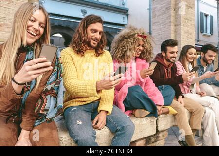 Group friends using mobile smartphone outdoor - Trendy young people having fun with new technology apps for social media phone Stock Photo