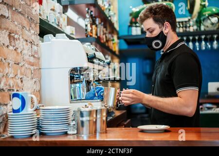 Side view of male barista preparing aromatic coffee in coffee maker Stock Photo