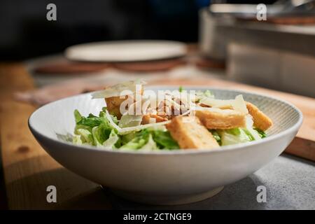 Bowl with delicious salad made with meat,cheese and fresh green salad leaves placed on kitchen counter in restaurant Stock Photo