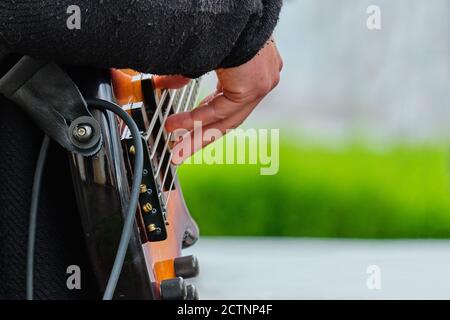 Musician holds a musical instrument guitar and plays on the street. Stock Photo