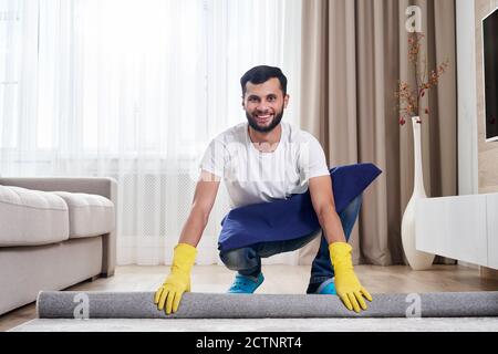 Close up of man unrolling carpet. Cleaning service concept Stock Photo
