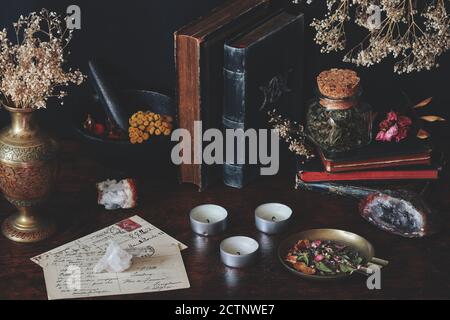 A collection of old vintage books on wiccan witch altar. Worn books placed on black table, with nature themed items on it Stock Photo