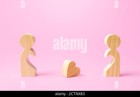 Figurines of people separated from each other and a lost heart. Breakup, end of love. Relationship problems of the couple. Take the first step towards Stock Photo