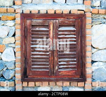 Old wooden mediterranean window shutters closed in the stone house Stock Photo