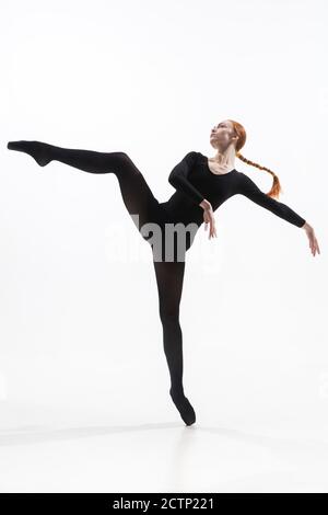 Elegance. Young and graceful ballet dancer in minimal black style isolated on white studio background. Art, motion, action, flexibility, inspiration concept. Flexible caucasian ballet dancer. Stock Photo