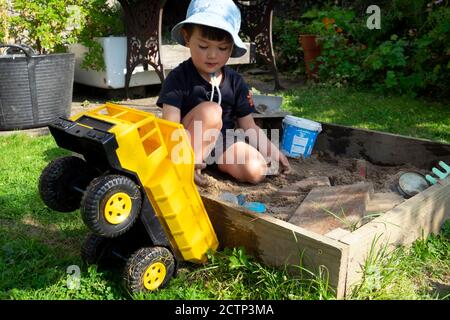 Child boy 3 years playing on a sunny day in a sand box sand pit in a garden in autumn, the fall September 2020 Carmarthenshire Wales UK   KATHY DEWITT Stock Photo